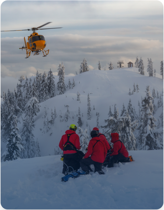 Search and rescue helicopter hovering over a snowy mountain as a SAR team prepares a rescue on Global Search and Rescue Day